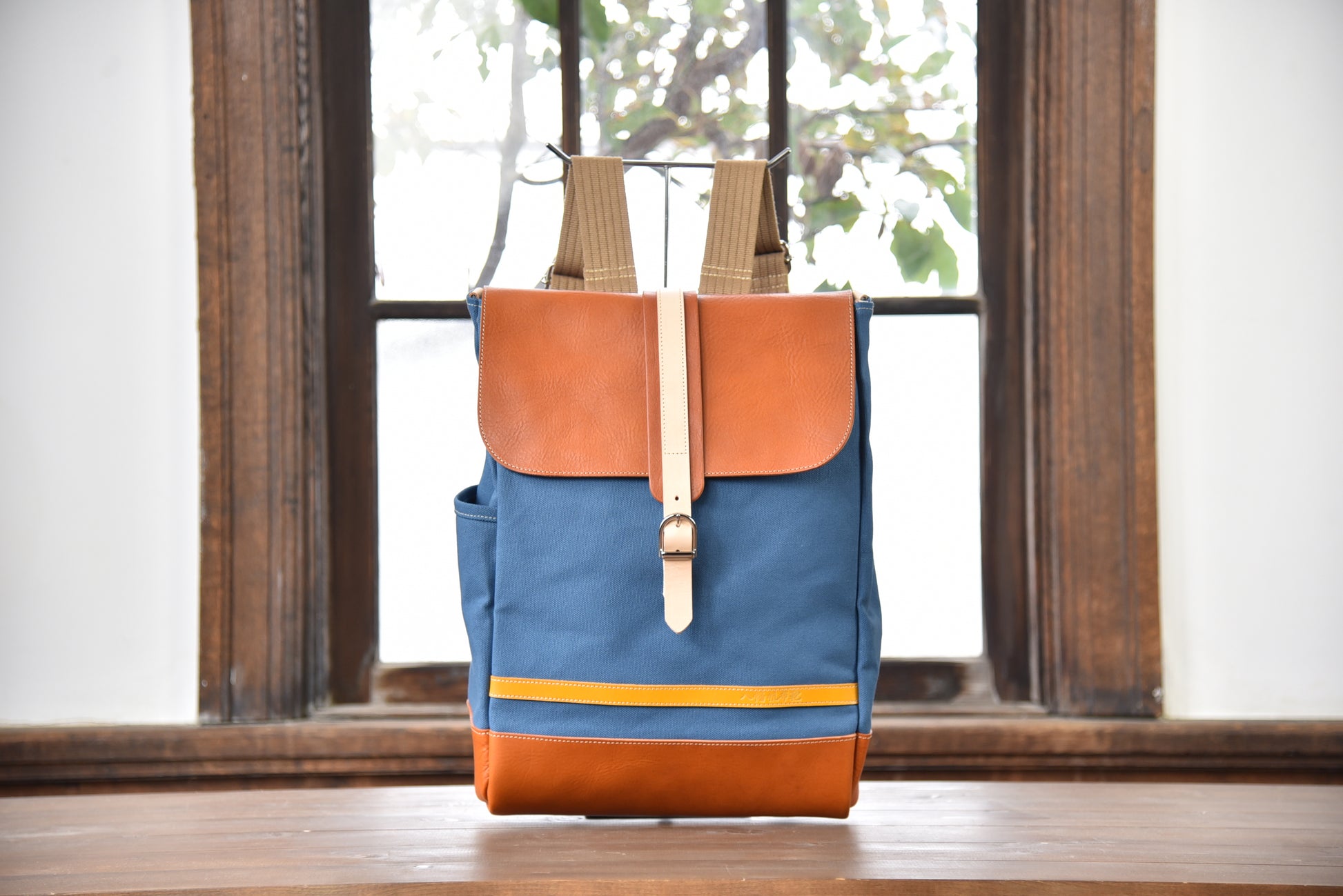 MUDITA HILL｜岡喜近江牛と高島帆布で作った　フラップ付きリュック【びわ湖ブルー・ブライトキャメル】正面から見た写真